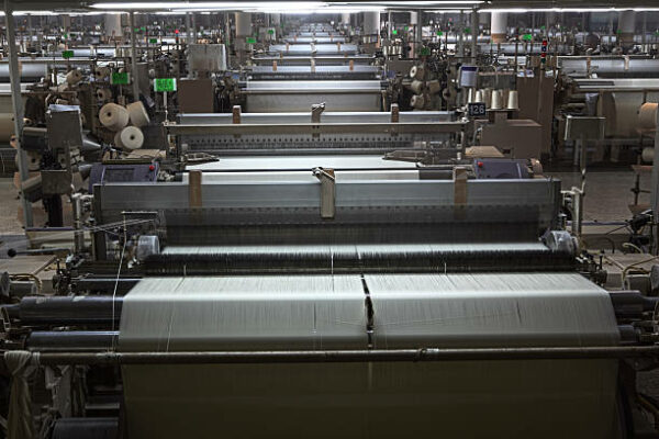 Rows of air jet Weaving looms in a textile factory.  *** Machine are operational hence some motion.